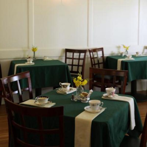 Small tables with green tablecloths and tea cups ready for tea service