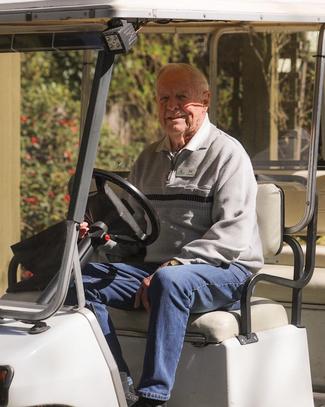 Smiling man driving a golf cart