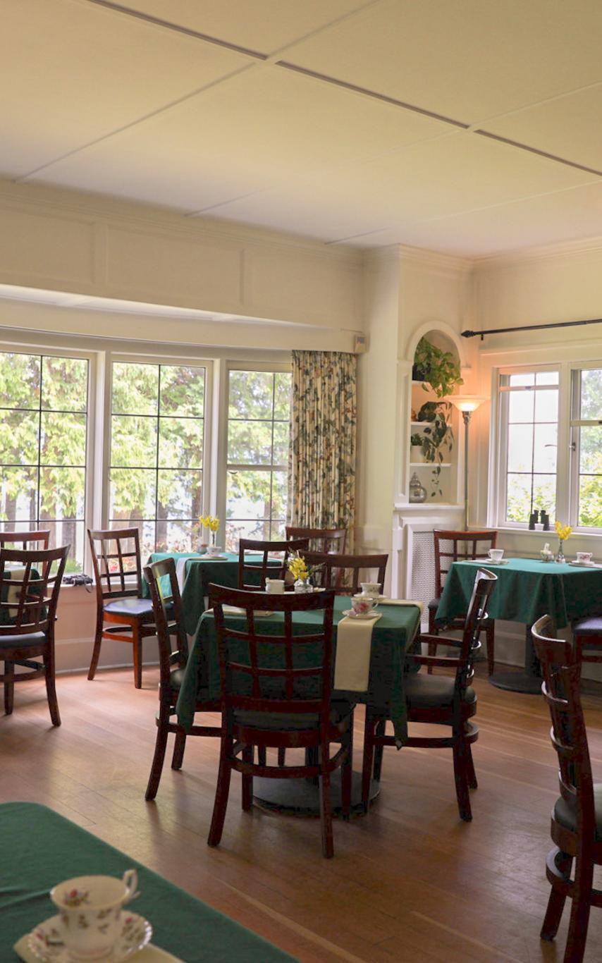 Eight small tables covered in green tablecloths set for tea service in a historic Drawing Room.